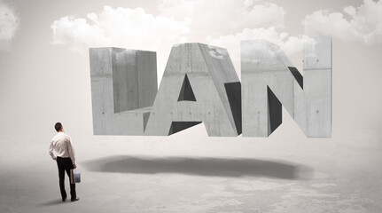 Obraz premium Rear view of a businessman standing in front of LAN abbreviation, modern technology concept