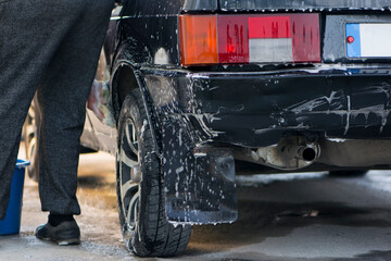Obraz na płótnie Canvas rear brake light black car in foam at the car wash close-up