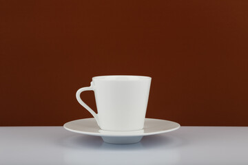 Cup of coffee on white table against brown background