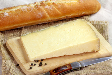 tranches de Cantal et baguette de pain sur une table
