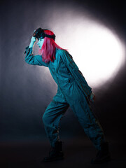 young woman with pink hair and in a jumpsuit uses virtual reality glasses, is in the game,