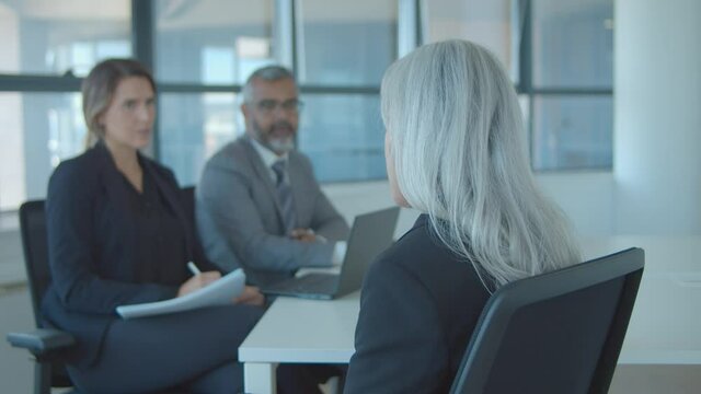 Back view of fair haired female professional meeting and talking to employer and HR manager at job interview. Static shot. Human resource and career concept