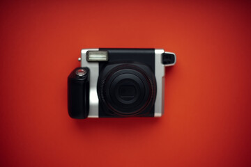 Fototapeta premium A modern black instant print camera on a bright red background.