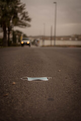 person holding a mask. mask on the ground, on the asphalt of a street