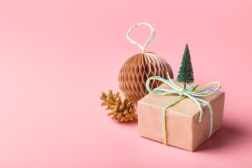 Christmas composition made with a gift and decorations on pastel pink background.