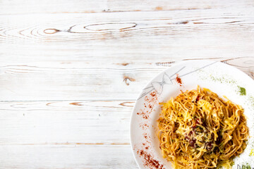 Fototapeta na wymiar Pasta with Bolognese sauce, cheese and spices in a large white plate on a white wooden background