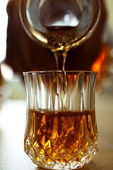 Close view of a bottle pouring whisky on a shot glass