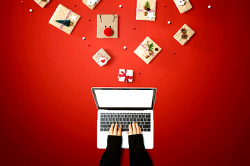 Person using a laptop computer with Christmas gift boxes from above