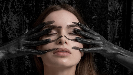 Female portrait with creative black colored scary hands