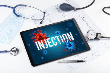 Tablet pc and doctor tools on white surface with INJECTION inscription, pandemic concept