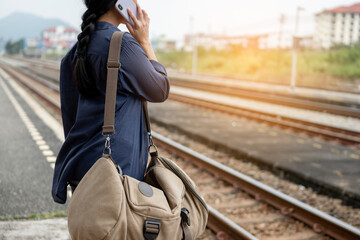 Traveler is waiting for train at the railway station. Women using smartphone for waiting train station platform.