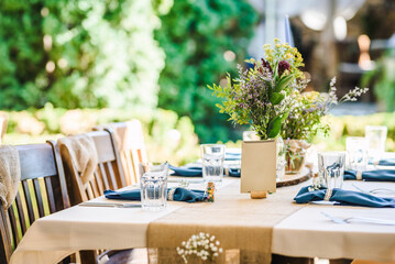 Outdoor wedding table decoration with fresh flowers and blank table cards. Special event table set up. Boho wedding decoration.