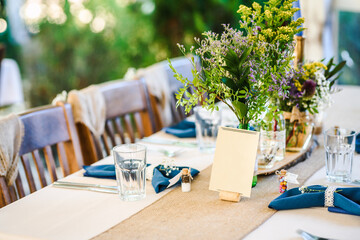 Outdoor wedding table decoration with fresh flowers and blank table cards. Special event table set up. Boho wedding decoration.