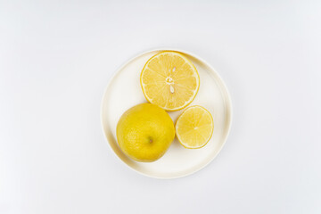Lemon sliced on round plate, white background. Recipe, vitamin, immunity concept. Top view, flat lay, copy space.