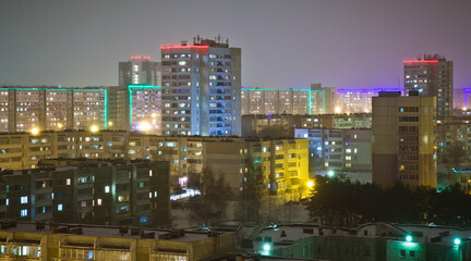 The cityscape of modern lit up living block in snowy winter in the evening . Many tall buildings in the skyline in Naberezhnye Chelny, Russia.