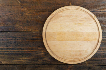 Round cutting board on a wooden table. Space for text.