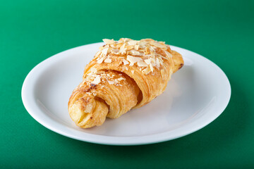 Croissant with almonds on a white plate.