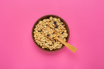 Cereal. Breakfast with muesli and raisins on a pink background. Space for text. Top view.