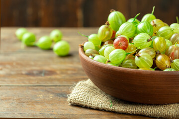 Sweet fresh gooseberry berry in a bowl on wood background.