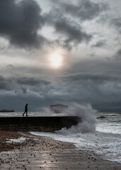 A man walking on groyne in Brighton during a stormy weather, UK