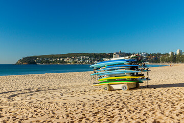 Colorful surfboards stacked on a trailer on the sandy Manly beach with Pacific ocean on the background. Sydney, Australia.