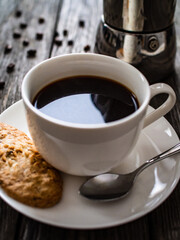 Cup of black coffee with biscuit on wooden background