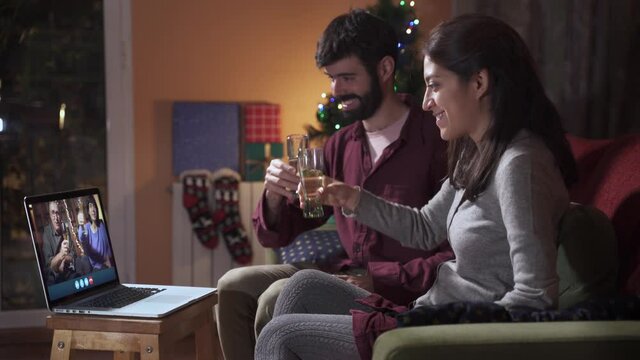 Family having a video call during Christmas. Toast in the distance for new year's eve. 2020 coronavirus Winter Holidays. Family members  separated but together online. 