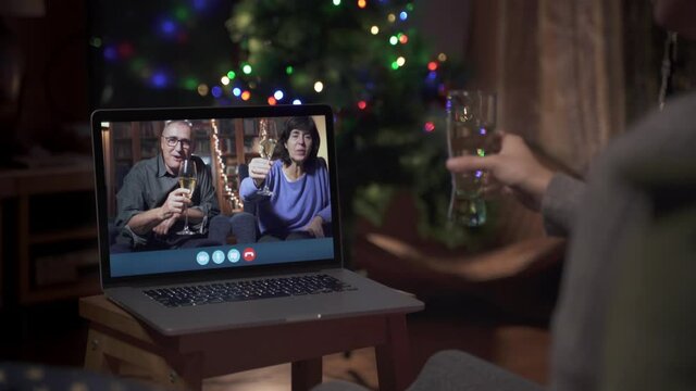 Family celebrating new year's through a video call. Family making a toast online through the computer. Christmas social distance. Coronavirus Confined Holidays. 
