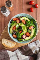 Organic healthy salad of avocado, tomatoes and mixed lettuce with olive oil