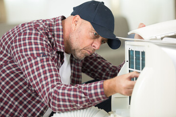 Naklejka na ściany i meble mature man working on air conditioning unit