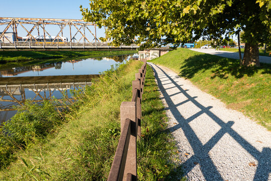 Pathway, foot path next to a river leading under a brige, in calm suburbian town a sunny summer day, out running, walking traveling, 