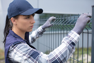 worker installing welded metal mesh fence