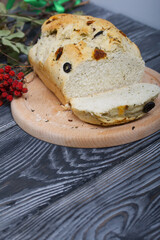 Focaccia bread with olives and sun-dried tomatoes. Nearby is a dried rowan branch with red berries. On pine boards.