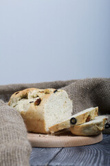Focaccia bread with olives and sun-dried tomatoes. Linen is nearby. On pine boards.