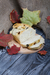 Focaccia bread with olives and sun-dried tomatoes. Nearby are linen and dried autumn leaves. On pine boards.
