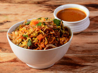 Traditional hyderabadi Vegetable / veg biryani with mixed veggies served with curry, selective focus