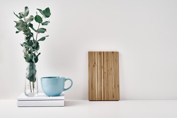 A mug, wooden board and a transparent vase with eucalyptus branches. Eco-friendly materials in interior decor, minimalism. Copy space, mock up
