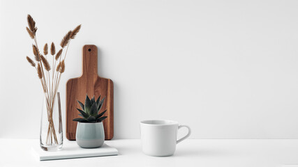 A mug, a potted houseplant, a clear vase and a wooden cutting board. Eco-friendly materials in the decor of the room, minimalism. Copy space, mock up