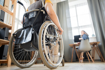 Fototapeta premium Wheelchair of young contemporary businesswoman moving towards colleague