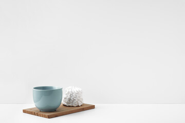 Blue mug and meringue cake on a white background. Eco-friendly and natural materials in decor and interior design, dessert. Copy space, mock up.