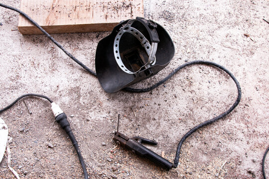 Welding equipment. Protective screen and rod-holder with welding electrodes wire. Electric welding equipment on dirty concrete floor.