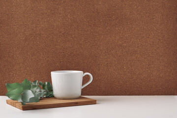 White cup and flowers on a chalkboard, cork background. Mock up, copy space.