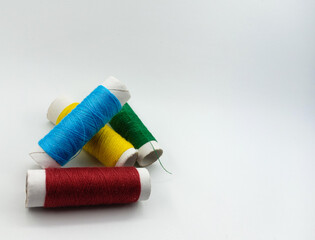 Close up detail of blue yellow red and green reels of thread isolated on white background. This is some of textile equipments