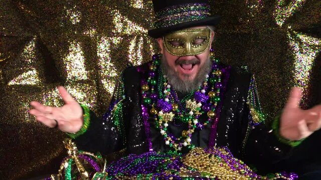 Happy Mardi Gras man in fancy costume with top hat holding pile of beads