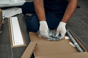 Furniture assembly process. Worker in overalls and white footwear. The choice of fittings for furniture. Do it yourself.