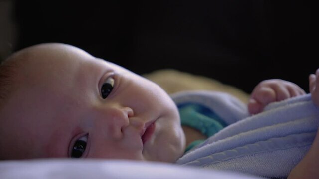 Close up on lovable baby girl pulling on her bib during the day and looking into camera