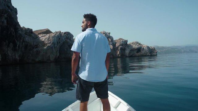 A young guy standing on a boat on the sea, enjoying his adventure in El jebha city Morocco.