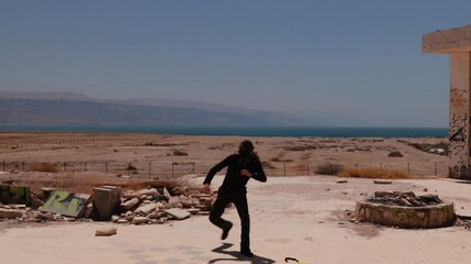Post apocalypse workout – man practicing Capoeira footwork between ruins, with a gas mask on his face.