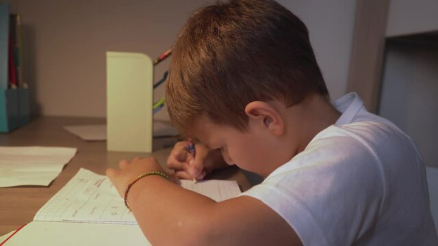 Footage of caucasian six years old boy, doing his homework lessons at home 4K