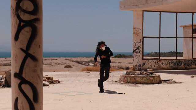 Post apocalypse workout &ndash; man practicing Capoeira between ruins, with a medical mask on his face.